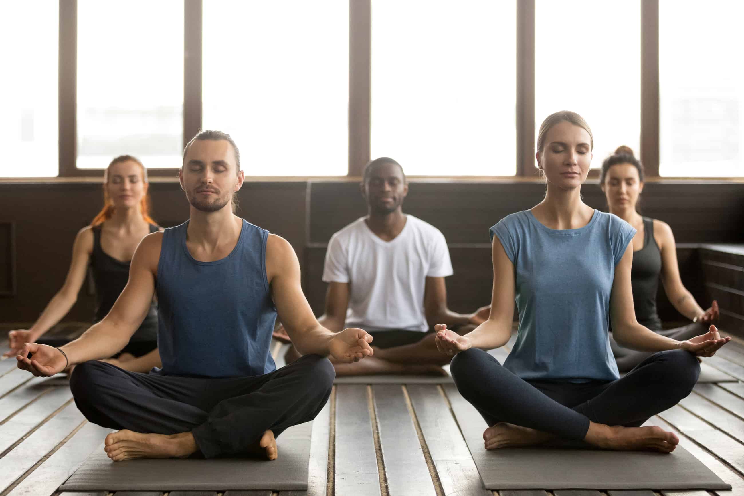 Werknemers in lotushouding tijdens bedrijfsyoga van Yoga op werk